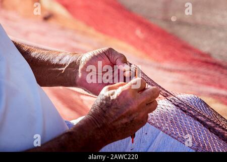 Pêcheurs réparant des filets de pêche sur le quai du port de Playa San Juan, Tenerife, îles Canaries, Espagne Banque D'Images