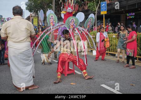 Pour le festival hindou de Thaipusam, un participant portant un Kavadi en l'honneur de dieu Murugan siège sur une chaise pour se remettre de l'épuisement; Singapour Banque D'Images