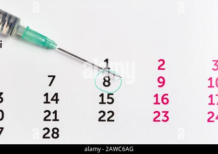La seringue avec vaccin tombe sur un calendrier. N'oubliez pas d'obtenir votre concept de vaccin, d'injection, de fertilité Banque D'Images
