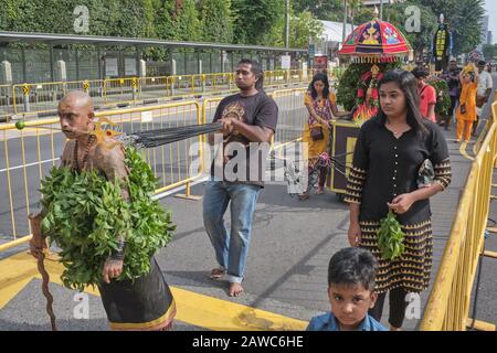 Pour le festival hindou de Thaipusam, un participant est accroché à des cordes, par lesquelles il tire un petit char festif; Little India, Singapour Banque D'Images