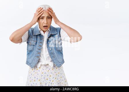 Choqué, anxieux paniqué femme senior confrontée à la fraude, tenant les mains sur la tête, secoué par le gaz, ramenée nervosité, s'inquiéter et sentir peur quelqu'un a volé Banque D'Images