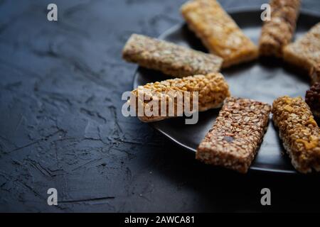 Différents types de barres de remise en forme en granola placées sur une plaque en céramique noire sur une table Banque D'Images