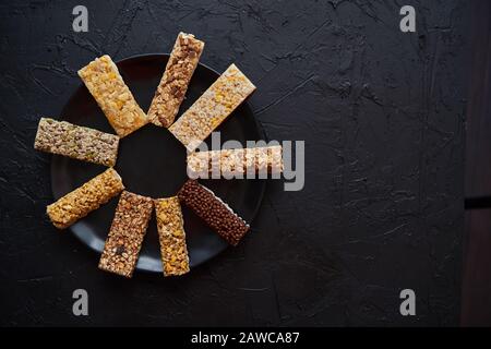 Différents types de barres de remise en forme en granola placées sur une plaque en céramique noire sur une table Banque D'Images