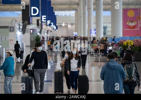 Les voyageurs ont vu porter des masques chirurgicaux comme une mesure protectrice contre le coronavirus mortel à l'aéroport international de Hong Kong.Des Centaines de vols entre les villes chinoises continentales et Hong Kong sont annulés comme la mesure de quarantaine obligatoire de 14 jours que les voyageurs devront rester à la maison ou à l'hôtel pour être mis en quarantaine prend en vigueur. Banque D'Images