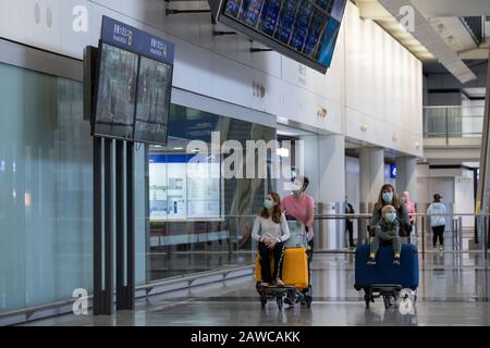 Les voyageurs ont vu le port de masques chirurgicaux comme une mesure protectrice contre le coronavirus mortel lorsqu'ils sortent du hall des arrivées de l'aéroport international de Hong Kong. Des Centaines de vols entre les villes chinoises du continent et Hong Kong sont annulés en tant que mesure de quarantaine obligatoire de 14 jours que les voyageurs devront rester chez eux ou l'hôtel à mettre en quarantaine prend effet. Banque D'Images