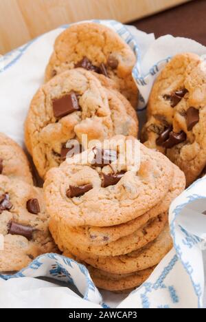 Une bande de cookies maison à puce au chocolat dans un panier recouvert d'une nouvelle serviette de cuisine propre. Banque D'Images