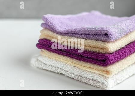 Serviettes en éponge pour la beauté et la santé. Une pile de serviettes multicolores se trouve sur un fond blanc. Style de vie, travaux ménagers. Espace de copie. Banque D'Images