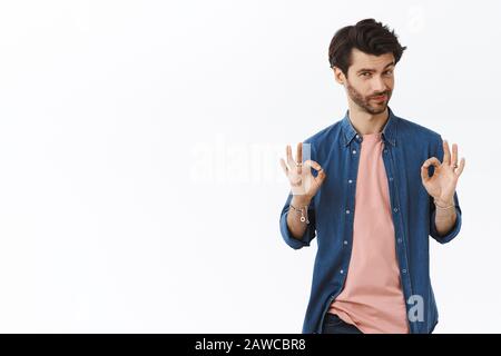 Guy sait comment faire la perfection. Un homme plein de charme et plein de confiance montrant bon, des signes ok et un smilk comme l'organisation de la meilleure fête de l'année Banque D'Images