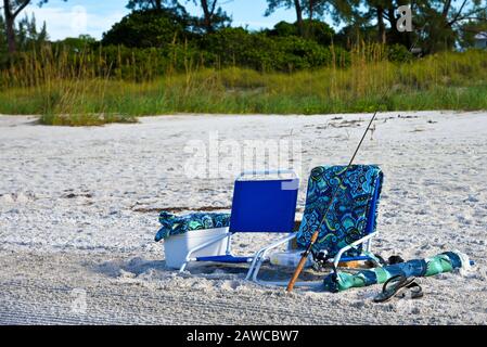 Deux chaises de plage avec une glacière, Fsihing Pôle, serviettes et un parasol sur la plage Banque D'Images