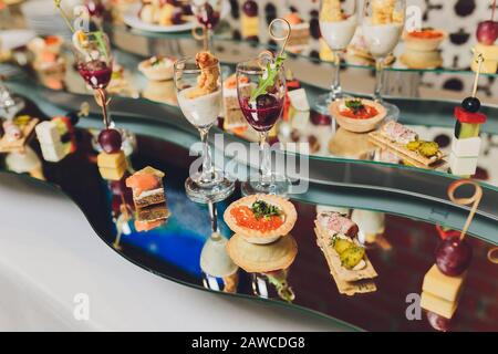 Différents canapés avec saumon fumé, tomates cerises au concombre et mozzarella servis sur une table Banque D'Images