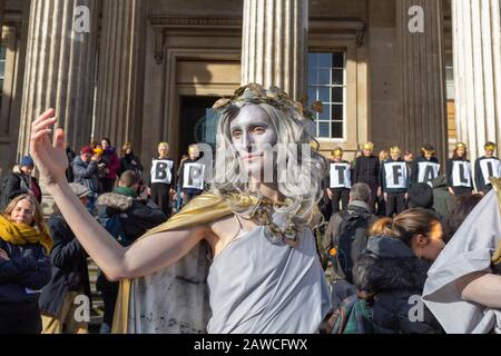 British Museum, Londres, Royaume-Uni. 8 février 2020. Activiste habillé comme une figure classique avec une peinture blanche pour le visage et une cape dorée pose devant le British Museum lors d'une manifestation BP ou non BP. Derrière eux, les manifestants tiennent des pancartes orthographiant « BP DOIT TOMBER », appelant le musée à couper les liens avec le parrainage des combustibles fossiles. Penelope Barritt/Alamy Live News Banque D'Images
