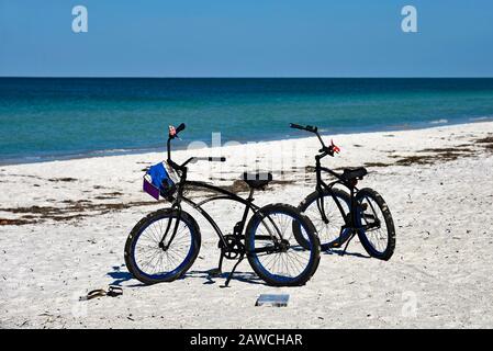 Deux Vélos avec paniers stationnés sur la plage de sable de l'île Anna Maria, en Floride Banque D'Images