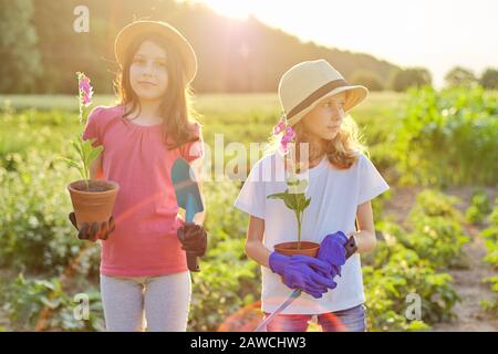Portrait de deux filles enfants avec fleurs en pots, gants, avec pelles de jardin Banque D'Images