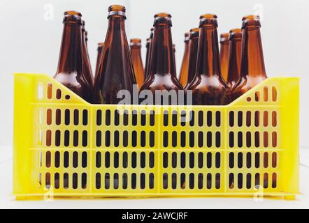 Caisse de bière jaune vintage poussiéreuse avec bouteilles de bière brune vides sur fond blanc Banque D'Images