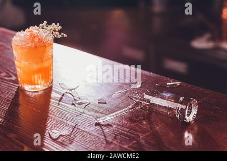 Verre de vin cassé sur comptoir de bar en bois Banque D'Images