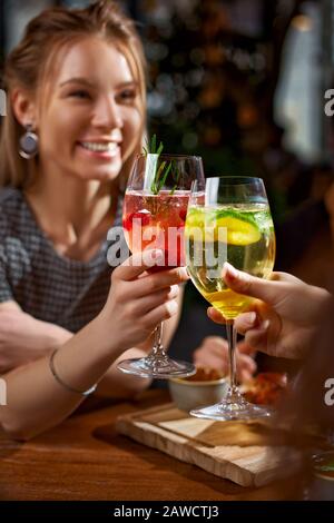 Deux filles boivent des cocktails aux couleurs rouge et jaune. Couleurs extrêmement vives. L'atmosphère de joie. Mise au point sélective. Banque D'Images