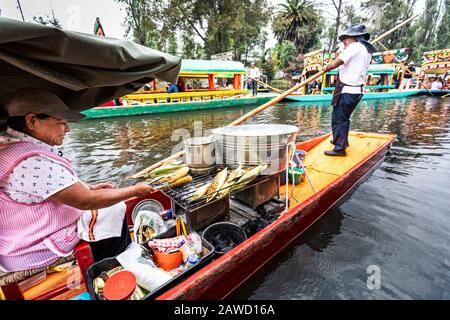 Les vendeurs vendent du maïs sur le rafle parmi les bateaux colorés appelés 'trajineras' de Xochimilco à Mexico. Banque D'Images