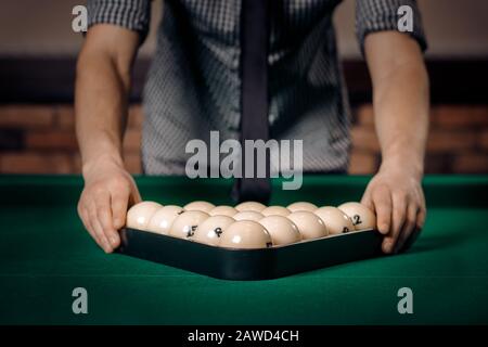 Le joueur masculin met des boules blanches avec un triangle dans le billard russe sur la table verte. Banque D'Images