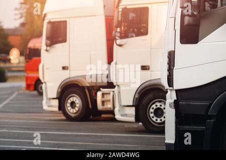 Camions sur camions, les voitures blanches sont stationnées dans le stationnement, prêtes à démarrer la logistique. Banque D'Images