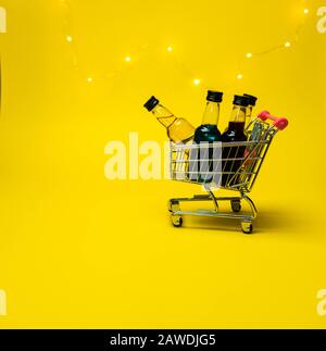 mini panier plein de petites bouteilles d'alcool fond jaune arrière Banque D'Images