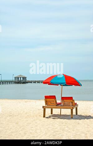 Parapluie de plage coloré et pont de baignade au soleil sur la plage Banque D'Images