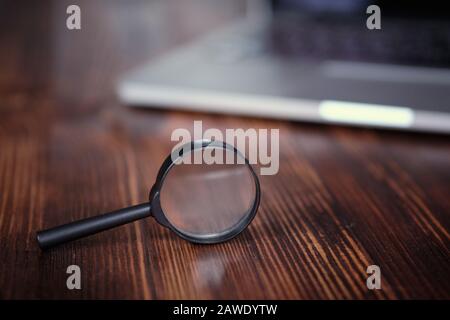 Un concept abstrait d'une loupe et d'un ordinateur portable comme une recherche d'informations dans un stagiaire pour les affaires. Gros plan. Banque D'Images
