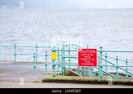 Zone à marée basse sujette au panneau d'avertissement d'inondation des marées au mur du port Banque D'Images