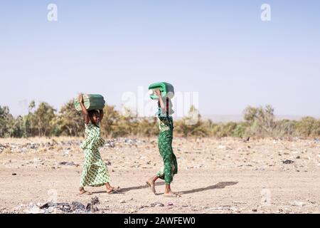 Joyeuse ethnicité africaine Juvenile Rassemblement de l'eau propre dans un village typique Banque D'Images