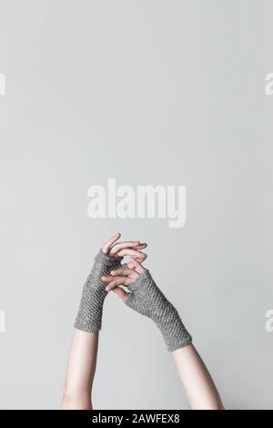 Mains féminines élégantes en gants tricotés gris, sur fond neutre avec espace de copie. Banque D'Images