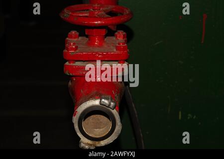 Vanne rouge installée sur le tuyau d'incendie. Ancien robinet industriel Banque D'Images