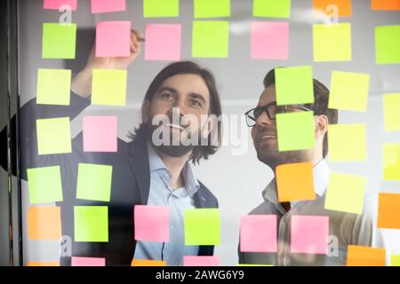 Deux hommes d'affaires souriants écrivant des tâches sur des papiers collants, le poster Banque D'Images