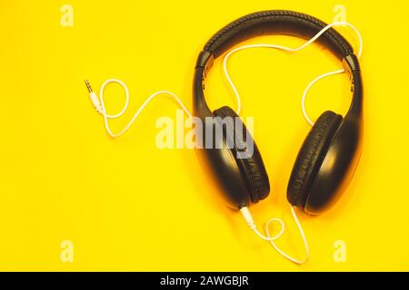 Casque noir avec câble blanc sur fond jaune. Écouteurs modernes Banque D'Images