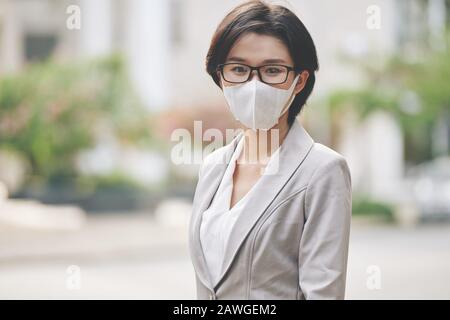 Portrait de la jeune femme d'affaires asiatique marchant à l'extérieur dans un masque médical protecteur pendant l'épidémie de coronavirus Banque D'Images
