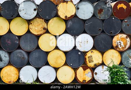 Beaucoup de vieux tambours rouillés sans marques visibles, spiralés en ordre dans de nombreuses rangées. Buissons verts au premier plan, vus à Bangkok, Thaïlande Banque D'Images