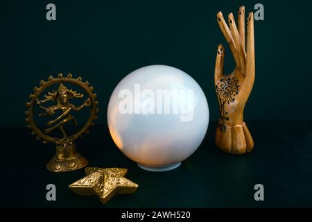 La vie ésotérique encore avec une boule de cristal et une main de bois, statuette du Dieu Shiva sur un fond noir Banque D'Images
