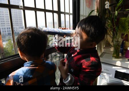 (200209) -- HEFEI, 9 février 2020 (Xinhua) -- fils de Fang Ji regarder vers l'hôpital Du second Peuple de Hefei sur le balcon à la maison à Hefei, capitale de la province d'Anhui en Chine orientale, 3 février 2020. Fang Ji, 34 ans, est une infirmière qui travaille en unité de soins intensifs de l'hôpital des deuxième Personnes de Hefei. Après l'éclosion du nouveau coronavirus (2019-nCov), Fang et ses collègues restent 24 heures sur 24 à l'hôpital pour prendre soin des patients en équipe. Le balcon de la maison de Fang se trouve en face de l'hôpital. Pour réconforter deux petits fils qui la ratent mal chez eux, Fang leur a dit cela Banque D'Images