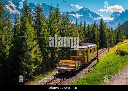 Fantastique expérience de voyage d'été, train touristique rouge électrique vintage avec montagnes suisses enneigées en arrière-plan, près de la gare de montagne de Murren, Be Banque D'Images