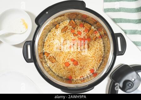 Riz à base de viande et légumes préparés dans plusieurs cuisinières, gros plan sur fond blanc, vue du dessus Banque D'Images