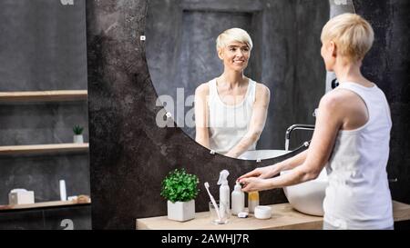 Femme D'Âge Moyen Se Laver Les Mains Debout Dans La Salle De Bains, Panorama, Espace Copie Banque D'Images