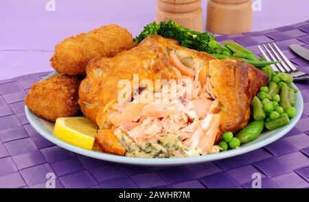 Saumon rose enveloppé dans un repas de pâte feuilletée avec croquettes et légumes de pommes de terre Banque D'Images