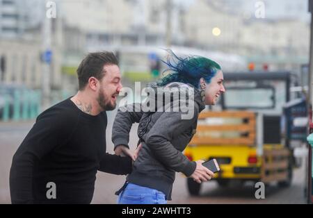 Brighton Royaume-Uni 9 février 2020 - un couple s'accroche sur le front de mer de Brighton dans des vents forts tandis que la tempête Ciara frappe la Grande-Bretagne avec des avertissements d'ambré étant donné dans tout le pays, les vents forts sont censés causer des dommages et un danger potentiel pour la vie: Crédit Simon Dack / Alay Live News Banque D'Images