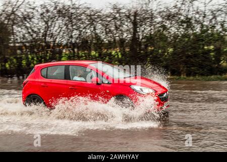 Une voiture qui traverse des eaux profondes et qui lance rapidement des jets d'eau sur une route à Kirkham, dans le Lancashire, au Royaume-Uni.Fév. 2020.Météo au Royaume-Uni ; les routes de la tempête Ciara ont été inondées à Kirkham.Crédit : MediaWorldImages/Alamy Live News Banque D'Images