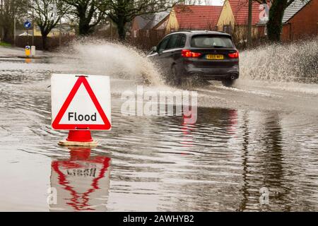 Une voiture qui traverse des eaux profondes et qui lance rapidement des jets d'eau sur une route à Kirkham, dans le Lancashire, au Royaume-Uni.Fév. 2020.Météo au Royaume-Uni ; les routes de la tempête Ciara ont été inondées à Kirkham.Crédit : MediaWorldImages/Alamy Live News Banque D'Images