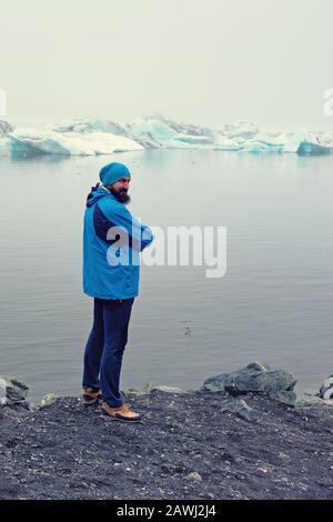 Homme dans un manteau bleu glacier Jökulsárlón à lake en Islande. Aventure Voyage concept nordique. Banque D'Images