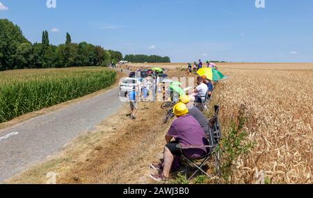 Paver Escaudoeuvres a Thun, France - 15 juillet 2018: Spectateurs attendant les cyclistes tandis que les véhicules techniques passent sur la route pavée pendant t Banque D'Images