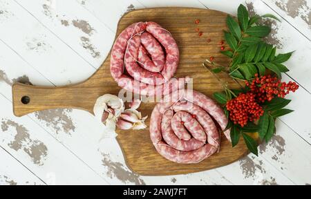 Espagnol longaniza es un embutido largo originario de España, saucisses de bœuf cru maison avec poivre rose sur le plateau de coupe Banque D'Images