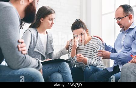 Comprendre les gens calmant la femme pleurant pendant la réunion de session de groupe à réadaptation Banque D'Images