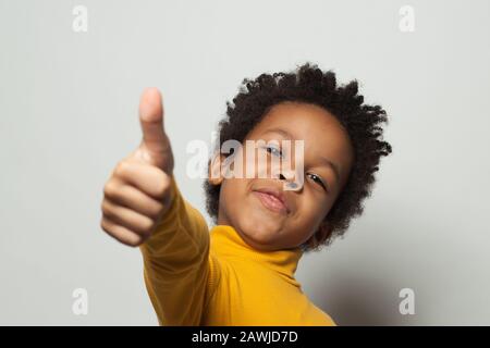 Un enfant afro-américain heureux montrant le pouce sur fond blanc Banque D'Images