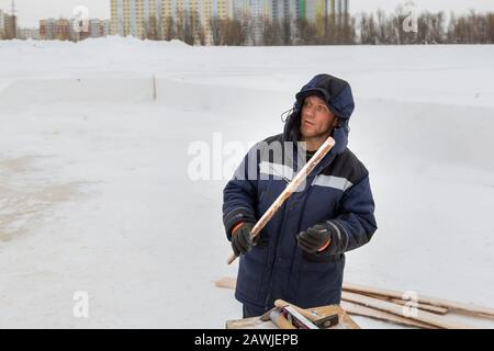 Travailleur en combinaison d'hiver avec une planche dans la main Banque D'Images