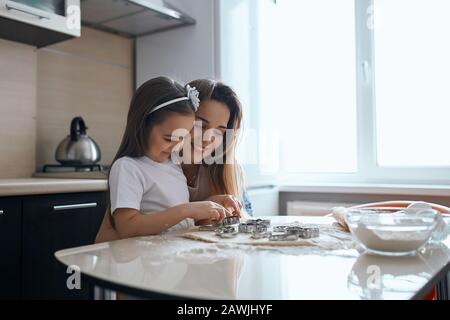 gai belle mère montre comment son enfant coupe des cookies, le bonheur, le sentiment positif et l'émotion. l'amour Banque D'Images